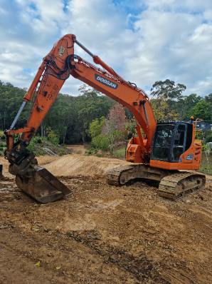 An orange excavator parked on a cleared dirt site