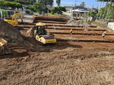 A large site being compacted with a roller and crew on the ground